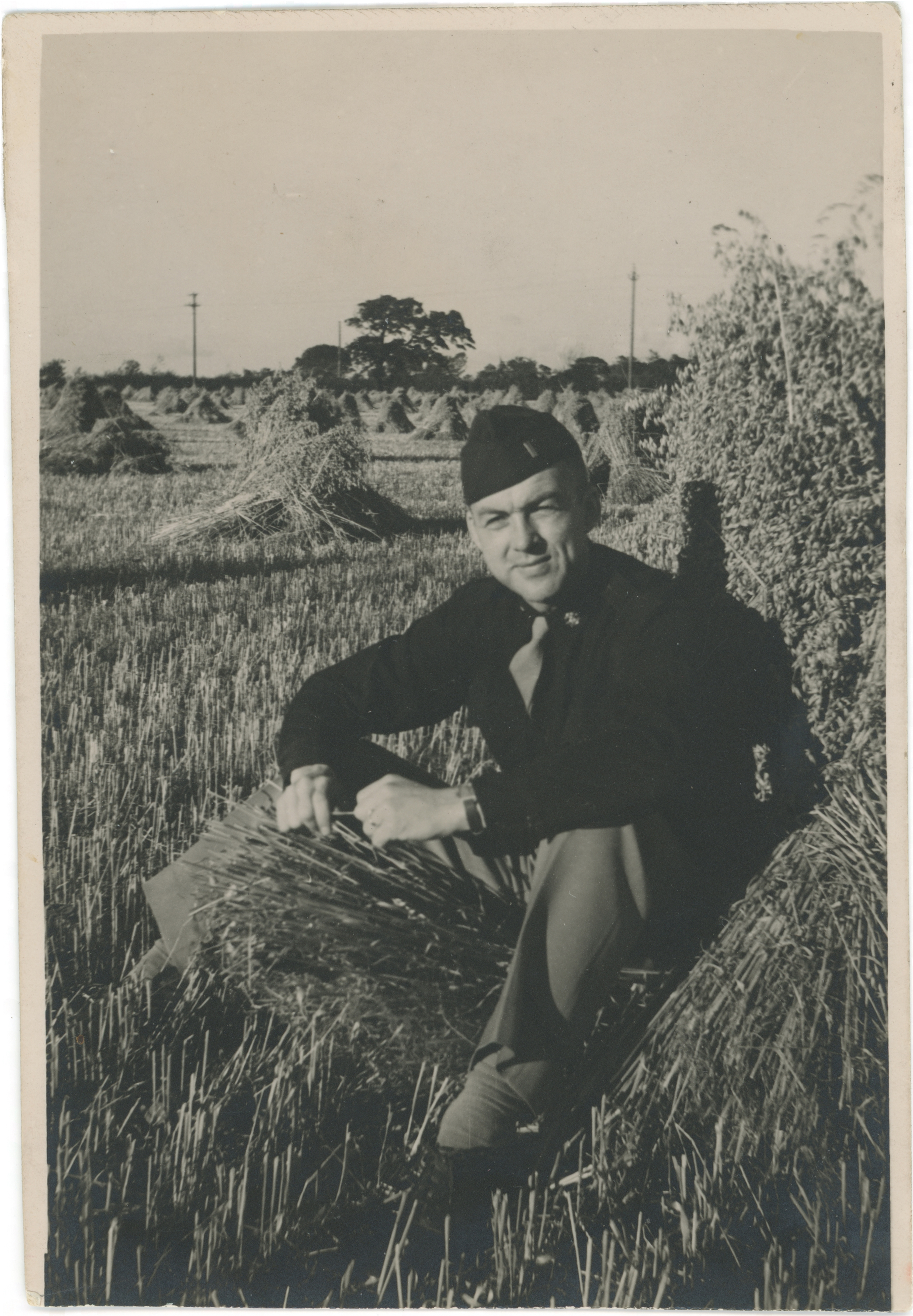 Phillip Milburn Nelson in uniform sitting in hay field, c.1943